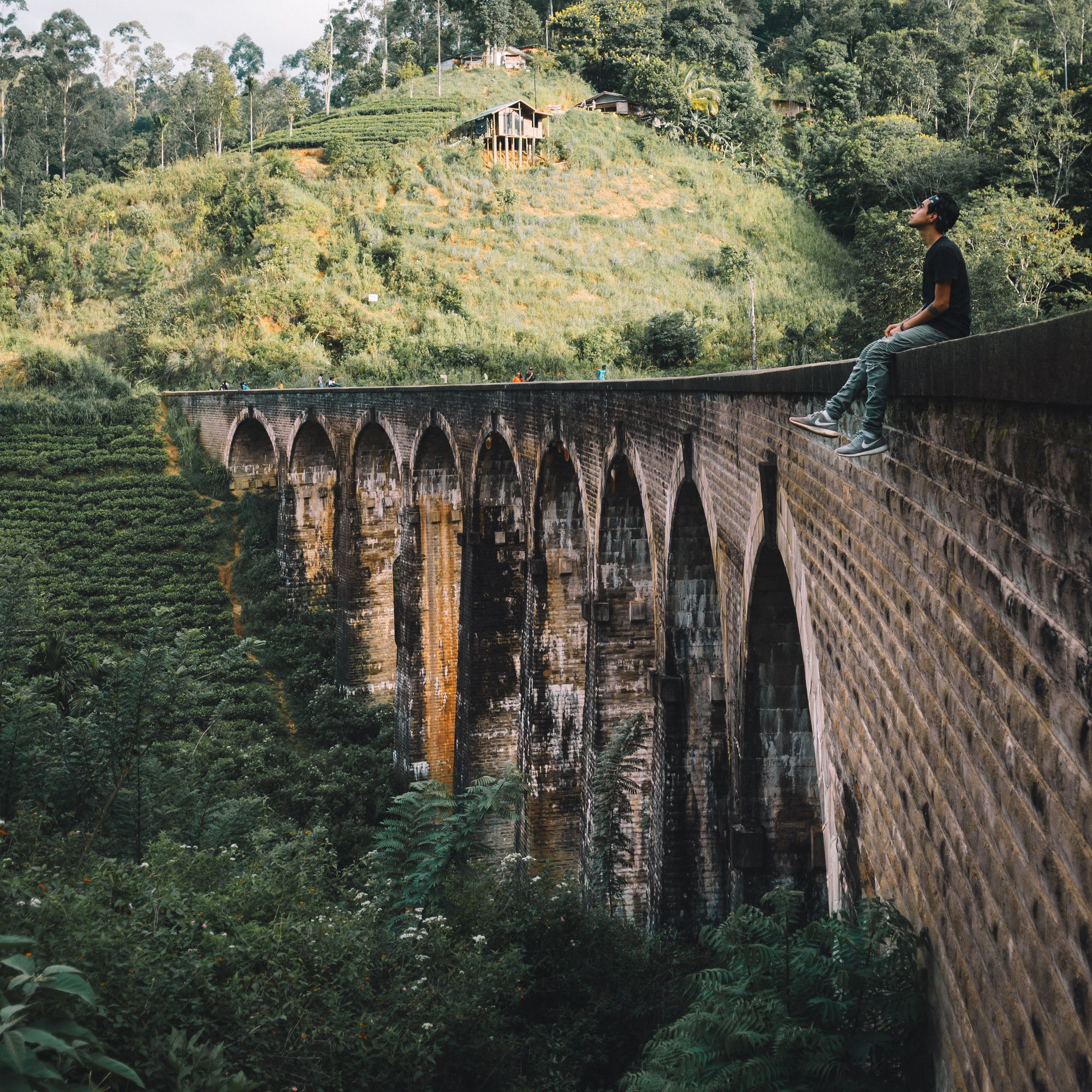 A man sitting on top of the Nine Arch Bridge in Ella, Sri Lanka
