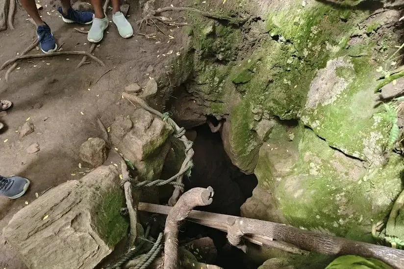 A hole in the ground that serves as the entrance to Nil Diya Pokuna in Ella, Sri Lanka