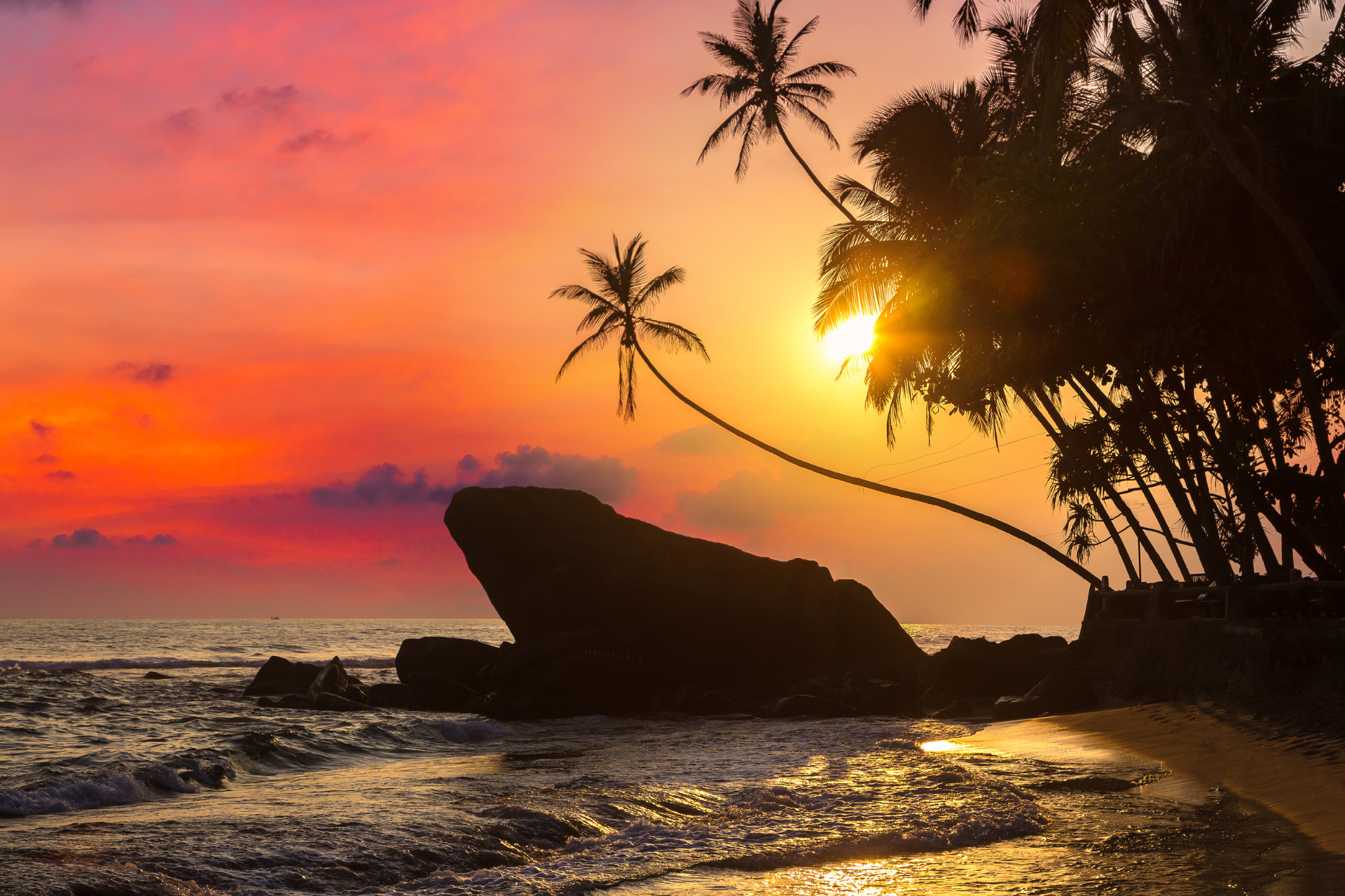 Sunset at Dalawella Beach near Galle, with beach, sea, palm trees and rocky outcrops.